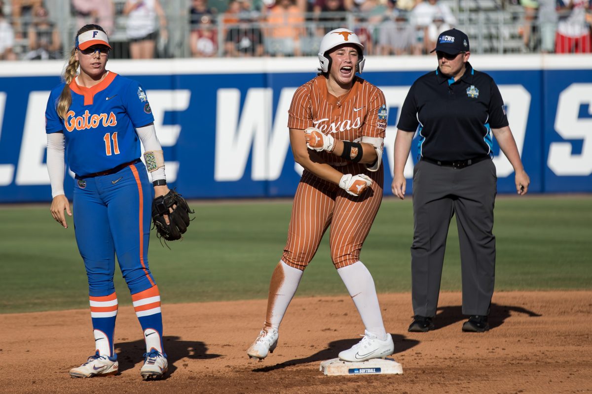 Jun 1, 2024; Oklahoma City, OK, USA; Texas Longhorns utility Katie Stewart (20) yells after hitting a double as Florida Gators infielder Mia Williams (11) looks on in the first inning during a Women's College World Series softball winners bracket game at Devon Park. Mandatory Credit: Brett Rojo-USA TODAY Sports
