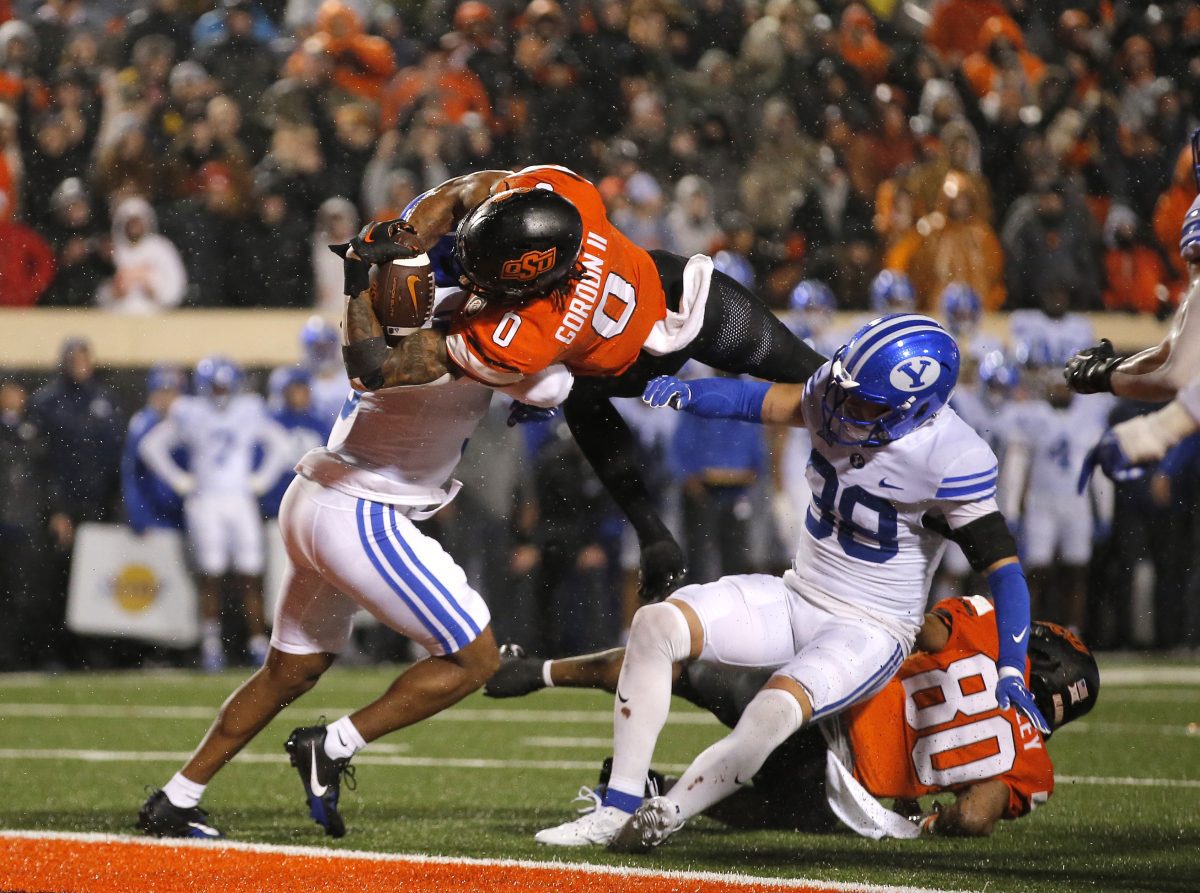 Nov 25, 2023; Stillwater, Oklahoma, USA; Oklahoma State's Ollie Gordon II (0) scores a touchdown in the second overtime against BYU's Eddie Heckard (5) and Crew Wakley (38) at Boone Pickens Stadium. Mandatory Credit: Sarah Phipps-USA TODAY Sports