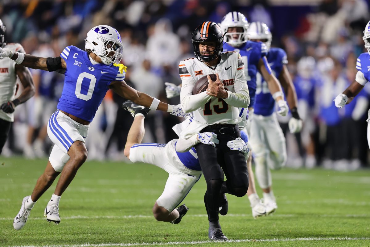 Oct 18, 2024; Provo, Utah, USA; Oklahoma State Cowboys quarterback Garret Rangel (13) is tackled by Brigham Young Cougars cornerback Jayden Dunlap (29) and cornerback Jakob Robinson (0) during the second quarter at LaVell Edwards Stadium. Mandatory Credit: Rob Gray-Imagn Images