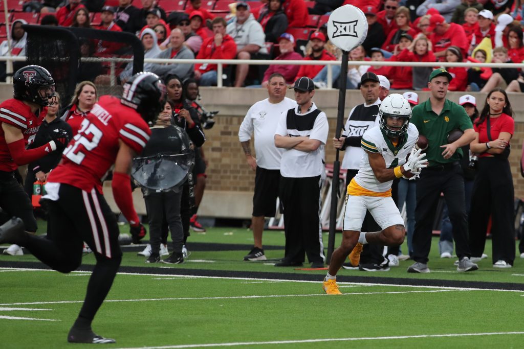Oct 19, 2024; Lubbock, Texas, USA; Baylor Bears wide receiver Monaray Baldwin (4) scores a touchdown against Texas Tech Red Raiders safety Devynn Cornwell (22) in the second half at Jones AT&T Stadium and Cody Campbell Field. Mandatory Credit: Michael C. Johnson-Imagn Images