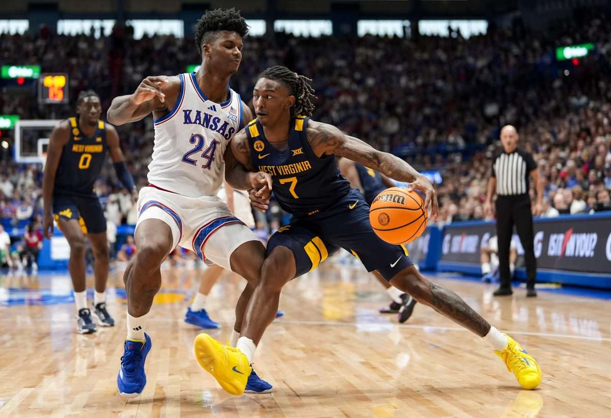 Dec 31, 2024; Lawrence, Kansas, USA; West Virginia Mountaineers guard Javon Small (7) drives against Kansas Jayhawks forward KJ Adams Jr. (24) during the first half at Allen Fieldhouse. Mandatory Credit: Jay Biggerstaff-Imagn Images