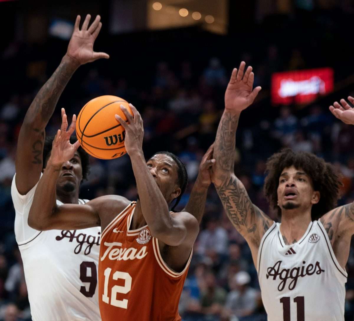 Texas Longhorns guard Tramon Mark (12) grabs a rebound in front of Texas A&M forward Solomon Washington (9) and forward Andersson Garcia (11) during their second round game of the SEC Men's Basketball Tournament at Bridgestone Arena in Nashville, Tenn., Thursday, March 13, 2025.