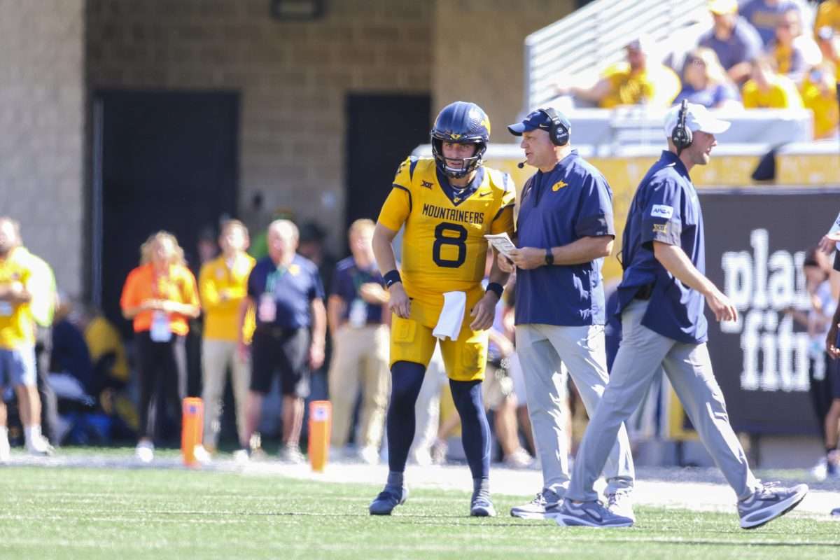 Aug 30, 2025; Morgantown, West Virginia, USA; West Virginia Mountaineers head coach Rich Rodriguez talks to West Virginia Mountaineers quarterback Nicco Marchiol (8) during the second quarter against the Robert Morris Colonials at Milan Puskar Stadium. Mandatory Credit: Ben Queen-Imagn Images
